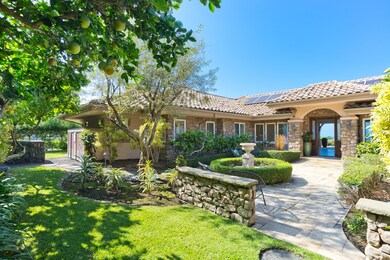 Courtyard entry with stone detailing, mature landscaping, and fruit trees.
