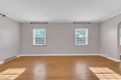 Empty room featuring ornamental molding and light wood-type flooring