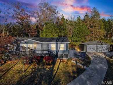 View of front of home featuring an outdoor structure, a detached garage, a deck, a front lawn, and crawl space
