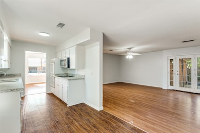 Kitchen with light countertops, dark wood-type flooring, white cabinets, and stainless steel microwave