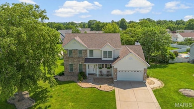 Traditional-style house featuring stone siding, driveway, an attached garage, covered porch, and a front yard