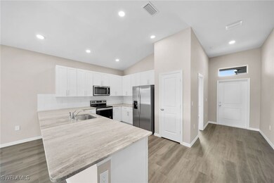 Kitchen with white cabinetry, appliances with stai