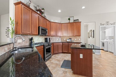 This charming kitchen offers elegant wood cabinets, sleek granite surfaces, and efficient appliances, making meal prep a breeze. Enjoy seamless access to the adjacent utility room for added convenience.