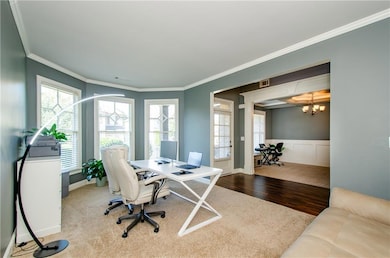 Carpeted office space featuring crown molding, wood finished floors, a wainscoted wall, and a chandelier
