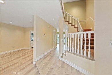 Front entry leading to hallway, Living room with fireplace, dining room, Kitchen with nook, family room, with  recessed lighting, newer paint, new waterproof vinyl flooring, and custom railing, leading to second floor.