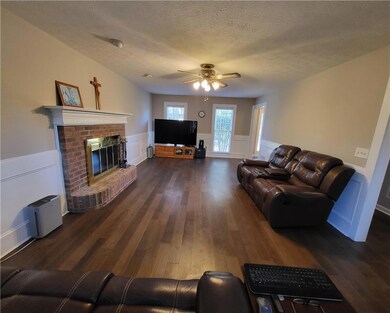 Living area with a brick fireplace, a textured cei