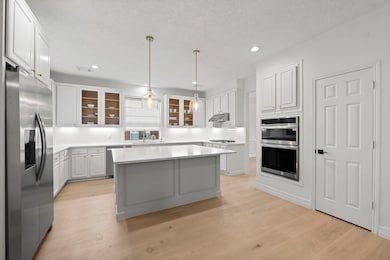 Showcase Kitchen with gathering island, glass-front cabinets & all new appliances. Preferred gas cooktop plus built-in refrigerator.