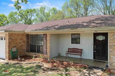 Property entrance featuring brick siding, a garage, covered porch, and roof with shingles
