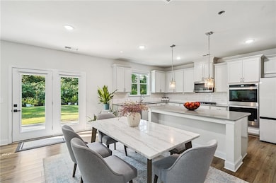 Kitchen featuring stainless steel appliances, tasteful backsplash, a center island, white cabinetry, and pendant lighting