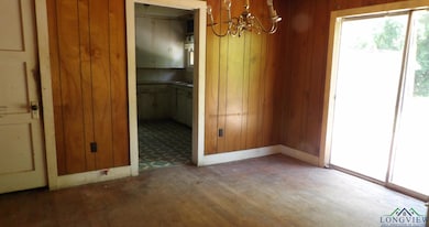 Unfurnished dining area with light wood-style flooring, a chandelier, healthy amount of natural light, and wood walls
