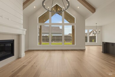 Unfurnished living room featuring a chandelier, a tiled fireplace, light wood-style floors, beamed ceiling, and high vaulted ceiling
