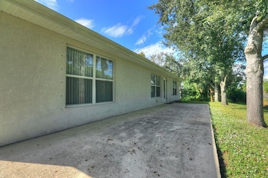 View of side of home featuring a patio, stucco siding, and a yard