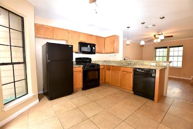 Kitchen with black appliances, a peninsula, a sink, a ceiling fan, and ornamental molding