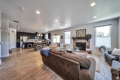 Living area with a chandelier, recessed lighting, a stone fireplace, healthy amount of natural light, and light wood-style floors