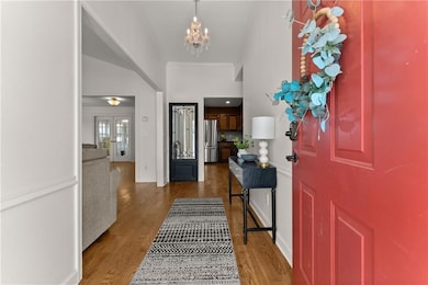 Foyer featuring a chandelier, stairway, crown molding, wood finished floors, and baseboards