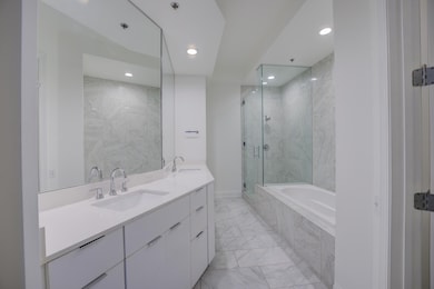 Bathroom featuring a sink, tiled tub, marble finis
