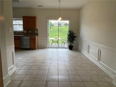 Kitchen with dishwasher, a decorative wall, light tile patterned floors, healthy amount of natural light, and wainscoting