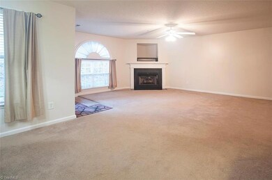 Large spacious living room with fireplace from perspective of the kitchen.