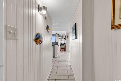 Hall with light tile patterned flooring, a textured ceiling, and wooden walls