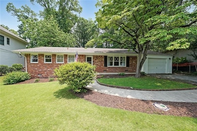 View of front of house featuring crawl space, brick siding, a garage, asphalt driveway, and a front yard