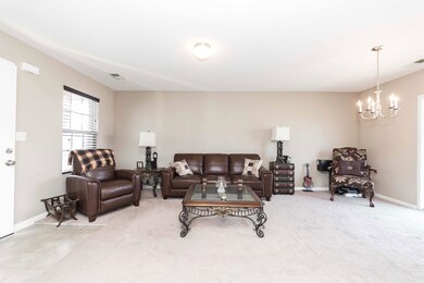 Living room featuring carpet floors and a chandeli
