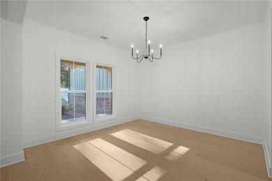 Empty room with light wood-type flooring and a chandelier