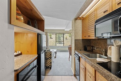 Kitchen with black appliances, a sink, light tile