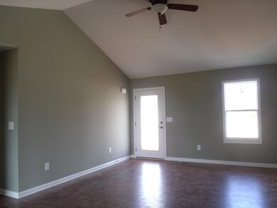 Vaulted living room with gleaming wood floors, ceiling fan, and lots of natural light coming in.
