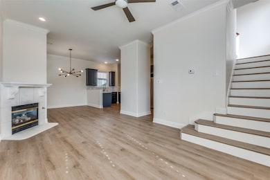 Unfurnished living room with a tile fireplace, crown molding, recessed lighting, a chandelier, and stairs