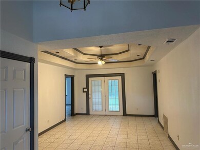 Living room with a raised ceiling and a ceiling fan, front entrance and garage entrance.