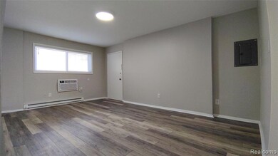 Empty room with wood finished floors, a baseboard radiator, electric panel, and an AC wall unit