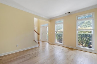 Foyer entrance with ornamental molding, light wood finished floors, healthy amount of natural light, and stairway