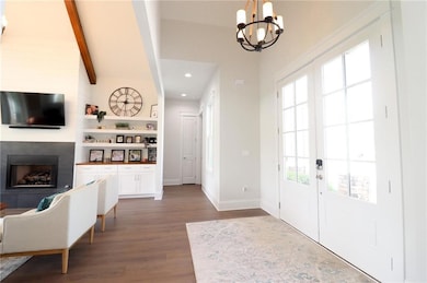 Foyer entrance with a large fireplace, wood finished floors, a chandelier, healthy amount of natural light, and beam ceiling