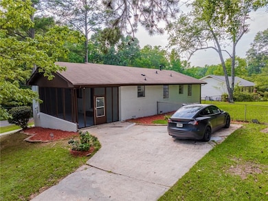 Back of property with a sunroom, brick siding, and driveway