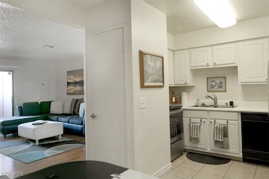 Kitchen with light countertops, white cabinetry, black dishwasher, stainless steel stove, and a textured ceiling