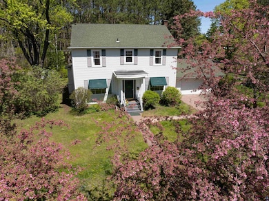Colonial house with a front yard, a chimney, a garage, and concrete driveway