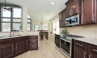 Notice that beautiful backsplash and how the vinyl plank floor continues to flow through the kitchen and beyond.