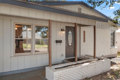 View of exterior entry featuring brick siding, board and batten siding, and covered porch