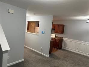 Hall featuring dark carpet and wainscoting