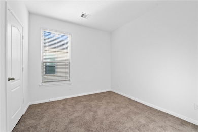 On the first floor, this secondary bedroom offers comfort and style with plush carpeting, neutral paint tones, recessed lighting, a large window with blinds, and a walk-in closet.