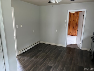 Spare room featuring ceiling fan, dark wood-type flooring, and a baseboard heating unit