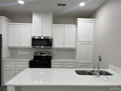 Kitchen with range with electric stovetop, stainless steel microwave, light stone counters, and recessed lighting