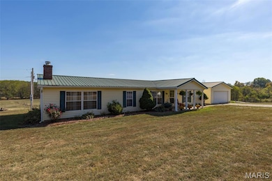 Single story home with a metal roof, a chimney, and a front lawn