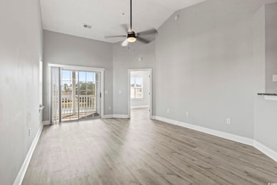 Spare room with high vaulted ceiling, wood finished floors, and a ceiling fan