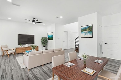 Dining room with stairway, a ceiling fan, wood finished floors, and recessed lighting