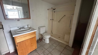 Bathroom featuring vanity, light tile patterned flooring, and a shower