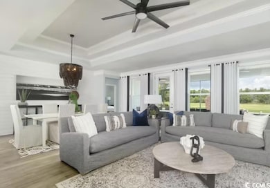 Living area featuring a tray ceiling, a ceiling fan, wood finished floors, and crown molding