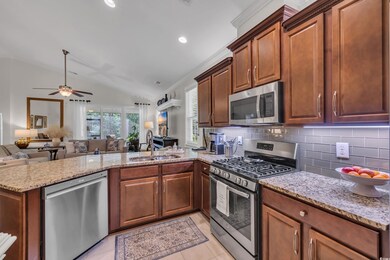 Kitchen featuring stainless steel appliances, a sink, open floor plan, a peninsula, and ceiling fan