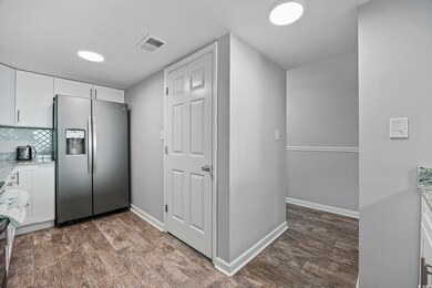 Kitchen featuring white cabinets, light stone counters, stainless steel fridge, and tasteful backsplash