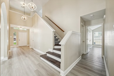 This view is looking toward the front of the home and shows the inside front entry area at the left, stairs leading to the upper level gameroom & bedrooms 2-4 and the hallway leading to the lower level primary suite.